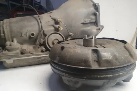 Zardzewiały sprzęgło hydrokinetyczne i skrzynia biegów leżą na stole.