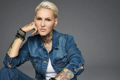 Agnieszka Chylińska w dżinsowej kurtce, z tatuażami i bransoletkami, w pozie sugerującej "never ending sorry".
