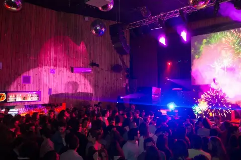 Festa al Macarena Club Barcelona, con luci stroboscopiche, DJ e fuochi d'artificio sullo schermo.