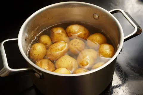 Ein Topf mit vielen Kartoffeln, die in Wasser kochen. Sind Kartoffeln gesund? Ja, sie sind eine gute Quelle für Vitamine und Mineralstoffe.