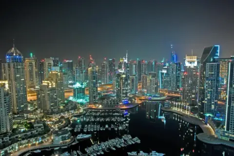 Widok nocą na drapacze chmur i przystań jachtową w Dubaju.