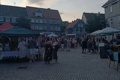 Menschen genießen den Abend auf dem Markt Remscheid. Stände mit Zelten und Tische unter Sonnenschirmen laden zum Verweilen ein.
