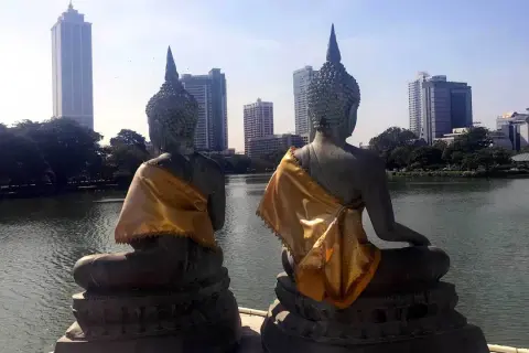 Dwie posągi Buddy z widokiem na nowoczesną panoramę stolicy Sri Lanki.