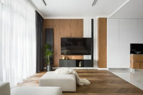 Un salon moderne avec un sol en parquet en chevrons, un mur texturé en bois et un meuble TV suspendu. Un mélange de carrelage et de parquet crée une transition élégante.