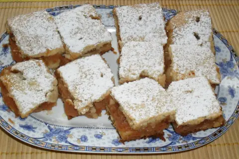 Na talerzu ułożono porcję 10 najlepszych ciast z jabłkami, posypanych cukrem pudrem.