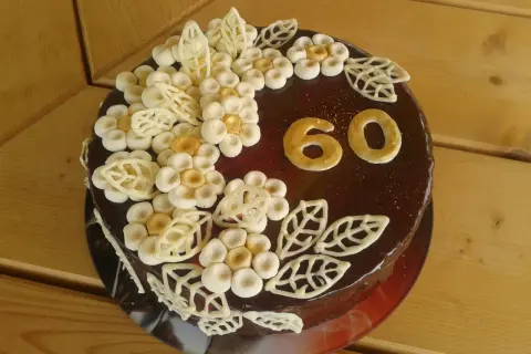 Elegancki tort na 60 urodziny dla mamy, ozdobiony czekoladowymi kwiatami i złotymi cyframi.