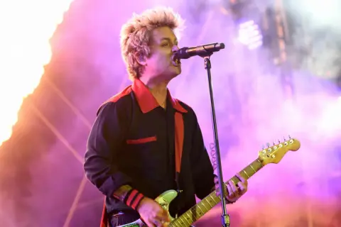 Billie Joe Armstrong von Green Day rockt die Bühne beim Rock am Ring Festival, umgeben von Flammen und lila Licht.