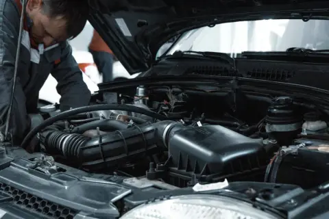 Mekaniker arbetar med bilens motor, troligen för att serva ac system bil.