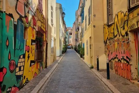Kolorowa uliczka z brukowaną nawierzchnią, ozdobiona dynamicznym street art graffiti na ścianach budynków.