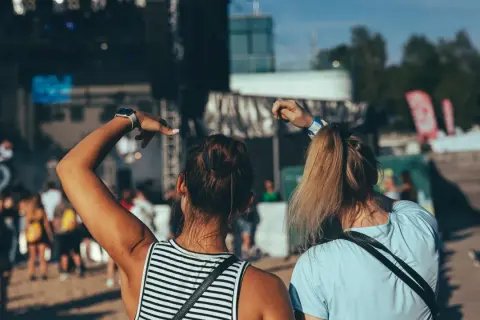 Dwie dziewczyny bawią się na koncercie podczas zielonego festiwalu, unosząc ręce w rytm muzyki.