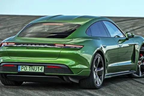 Zielony Porsche Taycan 4S z polskimi tablicami rejestracyjnymi PO-1NU14 na tle pustej drogi.