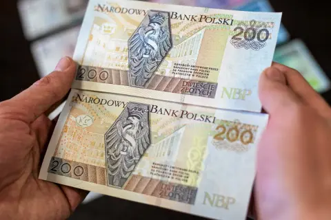 Dwie ręce trzymają banknoty 200 zł. Chcesz wiedzieć, jak wyprostować banknot? Oto rozwiązanie.