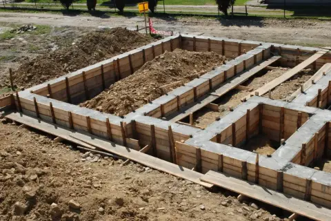 Betonowy fundament w drewnianym szalunku, gotowy do dalszych prac budowlanych.