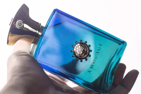 Dłoń trzyma luksusowe perfumy Amouage Figment w niebiesko-turkusowej butelce.