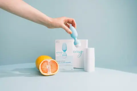 Main d'une femme tenant une sonde pour rééducation périnéale. Le produit, une sonde pour rééducation périnéale, est présenté avec des fruits. Pas d'effets secondaires connus.