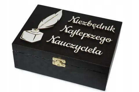 Czarna szkatułka z piórem i kałamarzem, ozdobiona napisem "Niezbędnik Najlepszego Nauczyciela". Idealna dedykacja dla nauczyciela.