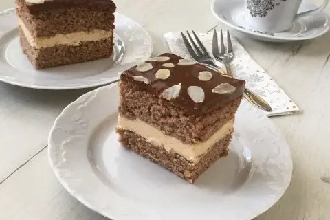 Pyszne ciasto z mascarpone i kajmakiem, polane czekoladą i posypane płatkami migdałów. Idealne na deser.
