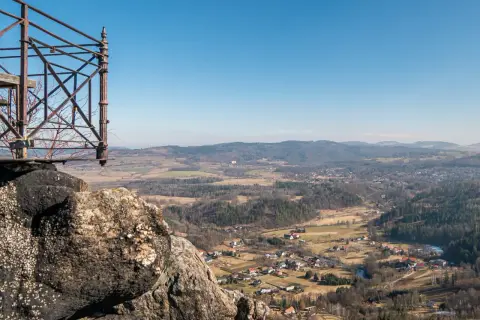 Widok z punktu widokowego na rudawy janowickie. W dole malownicza dolina z zabudowaniami i lasami.