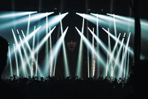Koncert Apashe w Warszawie: tłum szaleje pod laserami i fajerwerkami, artysta na ekranie.