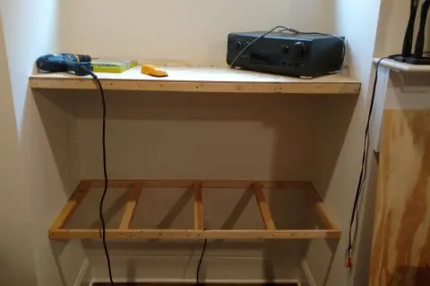 DIY project: a drill, level, and audio receiver sit on a wooden shelf, with a frame for another shelf below, showing how to hang shelves.