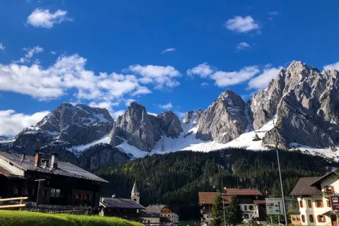 Villaggio alpino con case in legno e montagne innevate sullo sfondo. Un assaggio di cosa vedere in Carnia, tra natura e tradizione.