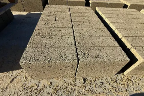 Stosy betonowych pustaków, każdy o standardowych bloczek betonowy wymiary, czekają na budowę.