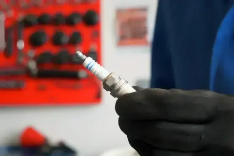 Main tenue une bougie d'allumage neuve, prête à être installée. Savoir quand changer les bougies d'allumage est essentiel pour le bon fonctionnement de votre moteur.