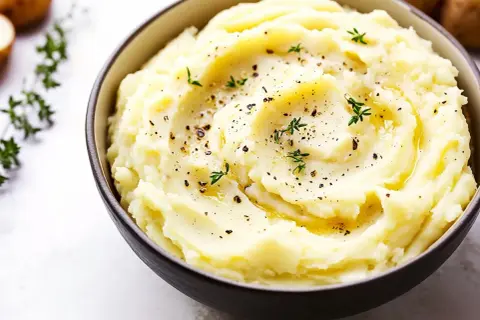 Krämigt potatismos i skål, toppat med örter och peppar. Perfekt som tillbehör till din middag, här är ett enkelt potatismos recept.
