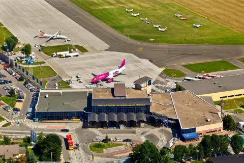 Lotnisko Wrocław na żywo: różowy samolot Wizz Air i mniejsze maszyny na płycie. Widać terminal i parkingi.