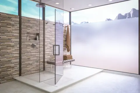 Ducha moderna con paredes de azulejos de piedra y mampara de **cristales translucidos**. Ventanal con vistas a montañas nevadas.