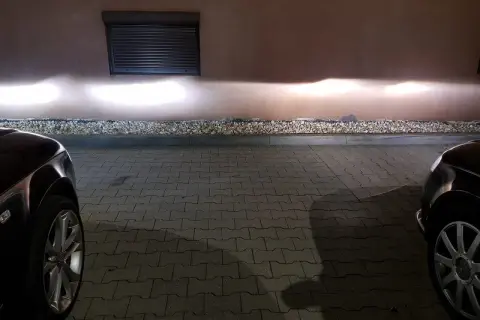 Jasne światła z przodu Audi A4 B6 oświetlają ścianę.