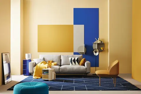 Modernes wohnzimmer blau gelb: graues Sofa, gelbe Decke, blaue Akzente und geometrische Muster auf dem Teppich.