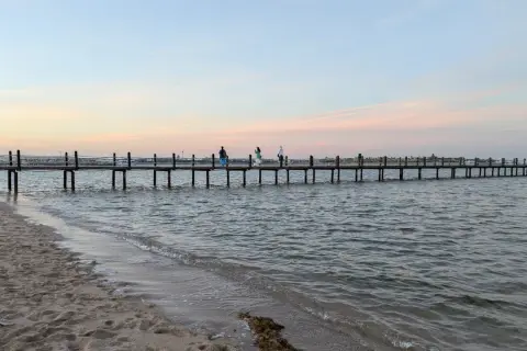 Piękna egipska pogoda we wrześniu. Długie molo na spokojnym morzu, piasek na plaży i pastelowe niebo.