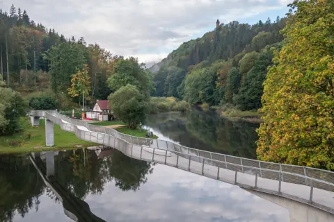 Nowoczesny most nad rzeką, otoczony jesiennym lasem. W oddali wieża widokowa, jedna z atrakcji Wałbrzycha i okolic.