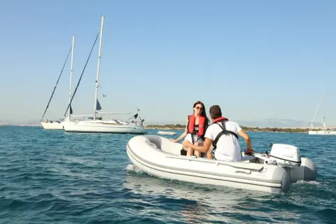 Coppia su una tender barca, con vele bianche all'orizzonte.