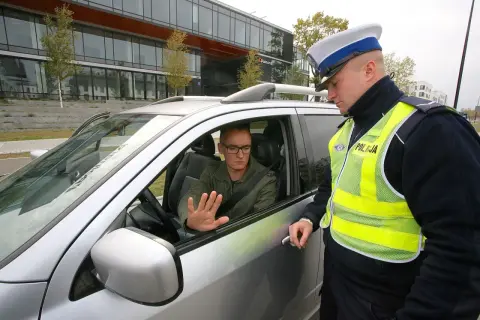 Policjant rozmawia z kierowcą, który może otrzymać zatrzymanie prawa jazdy na 3 miesiące.
