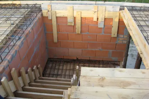 Budowa schodów drewnianych: szalunek z desek i cegieł, zbrojenie pod beton.