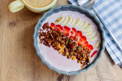 Un delicioso tazón de batido de bayas de acai con fresas, plátano, granola y almendras.