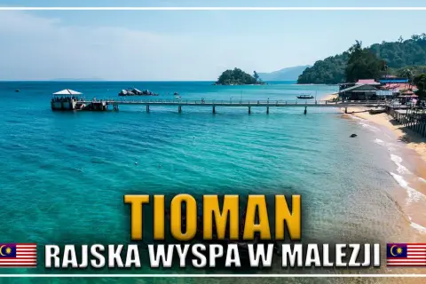 Malajska wyspa Tioman, z turkusową wodą, piaszczystą plażą i pomostem prowadzącym do lądu.