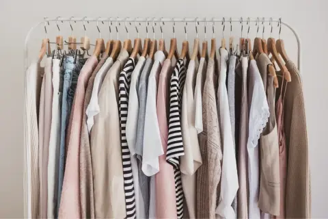 Kleiderständer mit einer Auswahl an Kleidungsstücken in neutralen Farben, die sich gut für eine Capsule Wardrobe eignen.