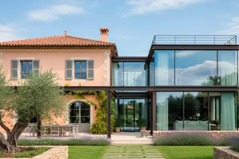Una casa tradicional con ampliaciones modernas de cristal y acero, rodeada de olivos y lavanda.