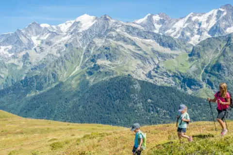 Famille en randonnée, profitant de leurs vacances montagne été. Paysage alpin spectaculaire sous un ciel bleu.