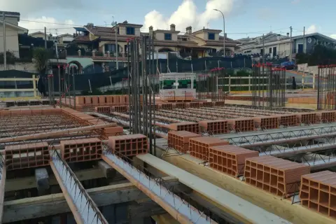 Cantiere edile con mattoni e armature in vista. Si sta preparando il miglior isolante termico per soffitto, con blocchi di laterizio pronti per la posa.