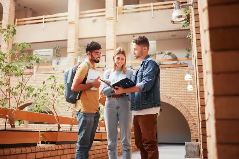 Drei Studierende planen ihren Auslandssemester Master in einem modernen Gebäude.