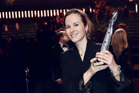 Uśmiechnięta Hania Rani z nagrodą, świętuje swoje nominacje.
