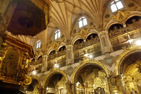 Interior del real seminario de San Carlos, con altares dorados, arcos ornamentados y techos abovedados.