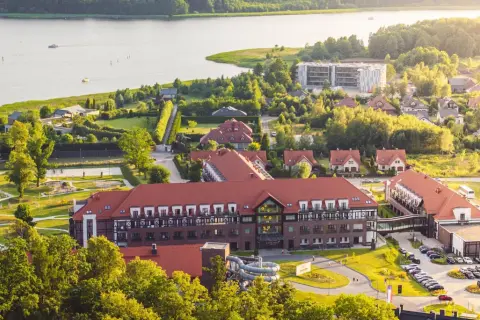 Widok z lotu ptaka na kompleks hotelowy Radisson z czerwonymi dachami, otoczony zielenią i jeziorem.