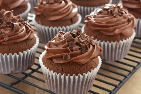 Schoko cupcakes mit cremiger Schokoladenfüllung und Schokostreuseln, auf einem Gitterrost.