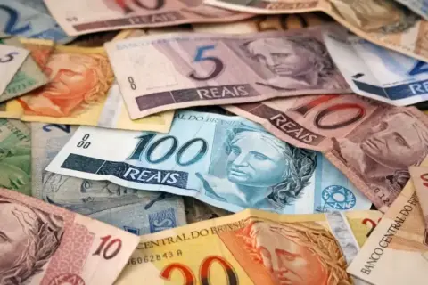 Stosy banknotów, w tym 100, 10 i 5 reali, stanowią walutę Brazylii.