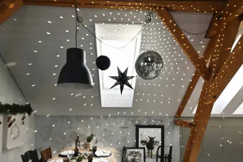 Une boule disco et une étoile décorent le plafond, projetant des lumières scintillantes. Une excellente idee deco plafond noel pour une ambiance festive.